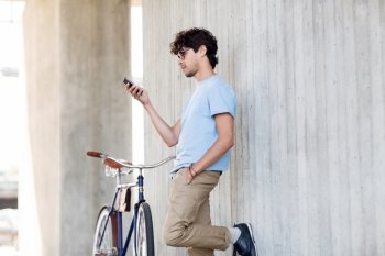 people, communication, technology, leisure and lifestyle - hipster man texting on smartphone with fixed gear bike on city street