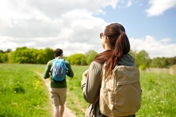 travel, hiking, backpacking, tourism and people concept - couple with backpacks walking along country road