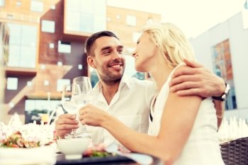 love, dating, people and holidays concept - happy couple drinking wine or water at open-air restaurant and clinking glasses