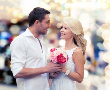 holidays, dating, people and dating concept - happy couple with bunch of flowers over lights background
