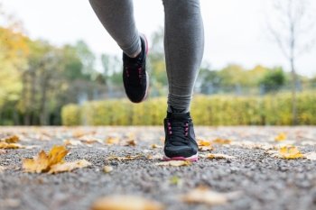 fitness, sport, people, wear and healthy lifestyle concept - close up of young woman running in autumn park