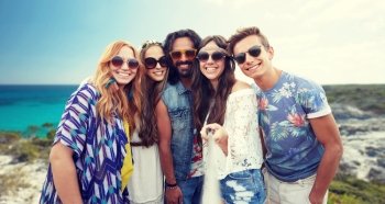 summer vacation, travel, tourism, technology and people concept - smiling young hippie friends taking picture by smartphone selfie stick over beach background