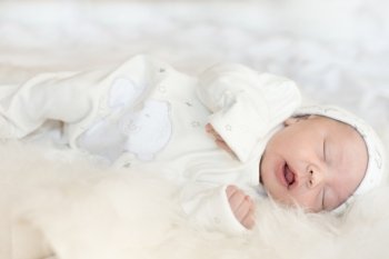Little newborn baby over a white fur
