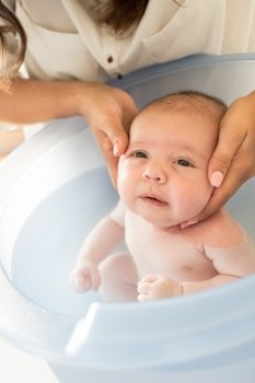 Adorable newborn baby having a bath by the mother