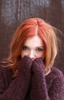 Portrait of a pretty teenage girl with redhaircovering her face with her hands