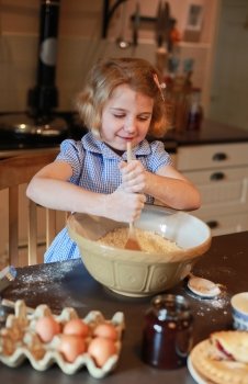 Pretty blonde haired girl mixing ingredients in a bowl for a pie