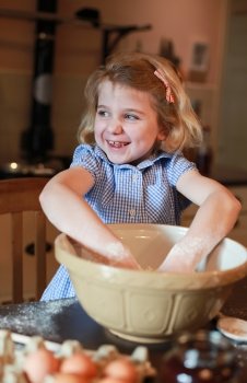 Pretty blonde haired girl baking wearing checked dress