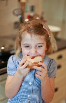 Pretty blonde haired little girl eating a cake with cherry on top