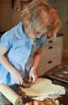 Young girl who is cutting out pastry with pastry cutter