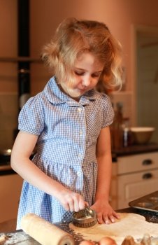 Young girl who is cutting out pastry with pastry cutter