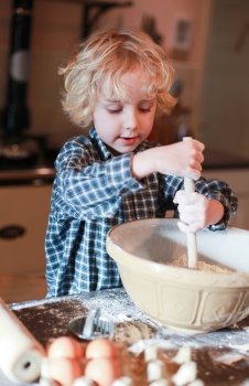 Little boy having fun mixing flour in a bowl