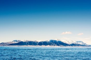 Snow on mountains in the blue ocean in Iceland