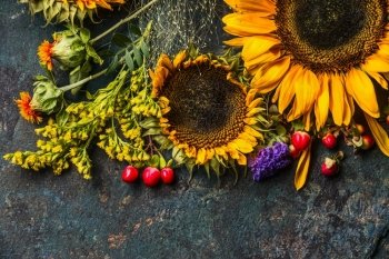 Floral autumn decoration with flowers and sunflowers on dark rustic vintage background, top view, border