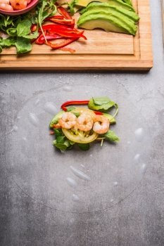 Rice paper rolls  with vegetables and shrimp, cooking preparation on gray stone background, top view