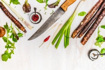 Fresh vegetables and seasoning ingredients for healthy cooking with kitchen knife on white wooden background, top view, border