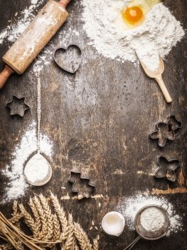 Christmas baking background with ingredients and  tools: Cookie Cutters, Cups, Mats, Rolling Pin, spoon . Dark, rustic, top view, frame