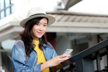 Young asian woman in casual style using smartphone while standing in the city outdoors background, people working outdoors with technology, urban lifestyle, people on phone