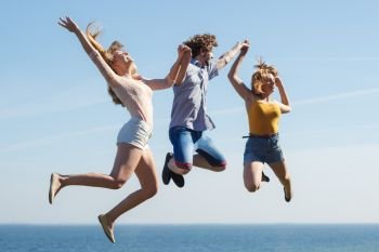 Carefree friends people jumping by sea ocean. Happy women and man having fun. Summer happiness and freedom.. Carefree friends jumping by sea ocean.