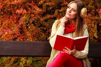 Woman fashion girl relaxing in autumnal park reading book sitting on bench. Fall lifestyle concept.. Woman relaxing in autumnal park reading book 