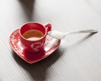 Coffee in a red cup, over wooden table, horizontal image