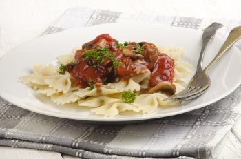 farfalle noodle with mushroom, tomato sauce and parsley on a plate