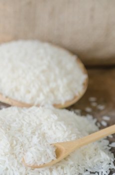 white rice  grains. white rice  grains with wooden spoon on wooden table