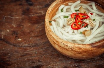 closeup of udon noodle in wood bowl on wooden floor background