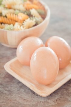 Fresh eggs on wooden plate with fusili , stock photo