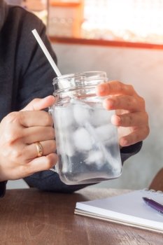 Woman’s hand holding a cold glass of water, stock photo