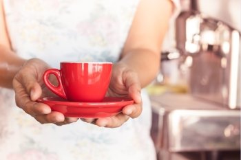 Woman’s hand holding red coffee cup, stock photo