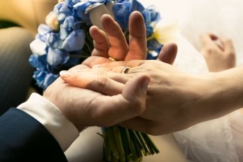 Closeup photo of groom holding brides hand in car