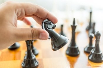 Closeup photo of male hand holding black horse chess piece