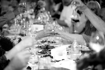 Closeup black and white photo of celebrating people clinking glasses with alcohol