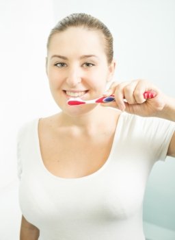 Closeup portrait of beautiful brunette woman brushing teeth