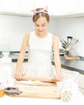 Portrait of cute girl rolling and kneading dough on wooden board
