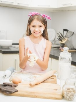 Happy smiling girl making dough for pie on kitchen