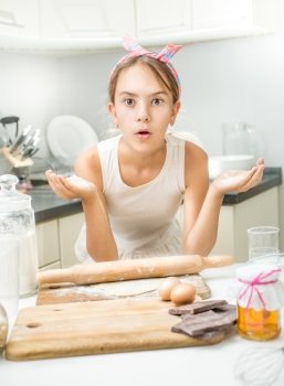 Portrait of funny girl making dough on kitchen