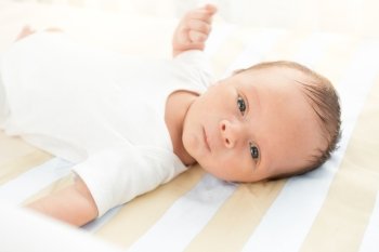 Closeup portrait of cute newborn baby lying in bed and looking at camera