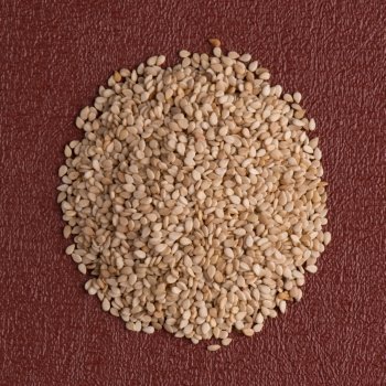 Top view of sesame seeds against red vinyl background.