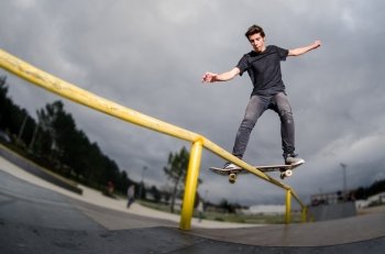 Skateboarder doing a board slide over the rail at the skate park.