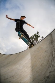 Skateboarder doing a tail slide on a croncrete pool at the skate park.