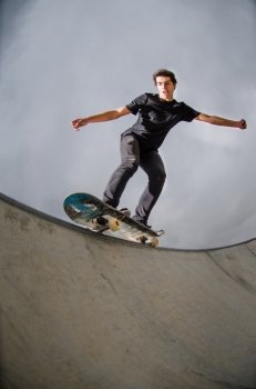 Skateboarder doing a grind on a croncrete pool at the skate park.