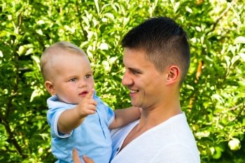charming caucasian baby boy with father in garden