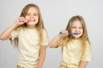 Two girls of four and six years of brushing their teeth toothbrushes. Two sisters brushing their teeth