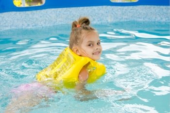 Girl learning to swim in the pool. Six year old girl Europeans bathed in a small suburban pool