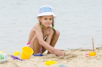 Five-year girl on the beach playing in the sand. Funny five-year girl playing with sand molds on the beach