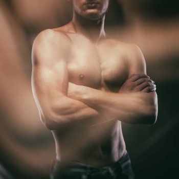 Muscular naked man on black background. Vintage processed