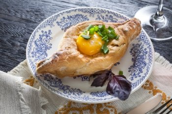 Khachapuri on plate with herbs. Top view. Khachapuri on plate with herbs