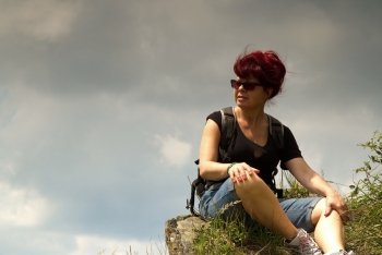 Poland in summer.Woman tourist sitting on top of a rock,looking at right sideWestern Carpathians called Bieszczady and resting.Close,vertical view.