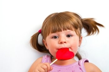 little girl eating red heart lollipop isolated on white